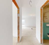 Im Bau befindliches Einfamilienhaus mit einem hellen Raum, verputzten Wänden und Betonboden.