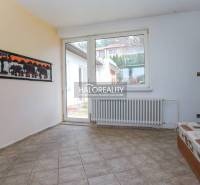 Innenraum eines Einfamilienhauses mit Fliesenboden, Sofa und großem Fenster.