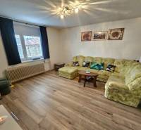 Wohnzimmer in einem Einfamilienhaus mit Sofa, Sesseln und einem Holzboden.