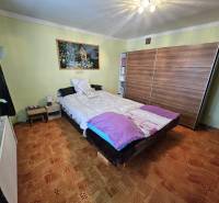 Schlafzimmer in einem Einfamilienhaus mit Bett, Schrank und Bodenbelag in Holzoptik.