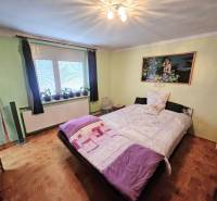 Ein Schlafzimmer in einem Einfamilienhaus mit einem Bett, grünen Wänden und einem Boden in Holzoptik.