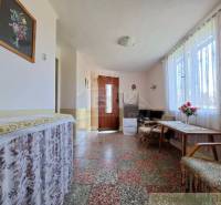 Innenraum eines Einfamilienhauses mit Mosaikboden, dekoriertem Tisch und Blumenschmuck.