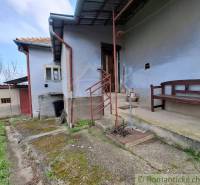 Ein Einfamilienhaus in Ľubá mit einer Bank auf der Betonterrasse und einem grasbewachsenen Hof.