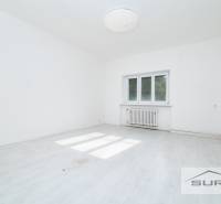 Ein leerer Raum mit weißen Wänden und einem Boden in Holzoptik in einer 4-Zimmer-Wohnung.