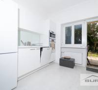 Küche mit weißen Schränken und Zugang zur Terrasse in einer 4-Zimmer-Wohnung.