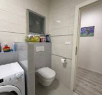 Badezimmer mit Waschmaschine, Toilette und Fliesen in einer 2-Zimmer-Wohnung.