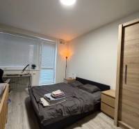 Schlafzimmer in einer 2-Zimmer-Wohnung mit Holzboden und einem Bett neben dem Fenster.