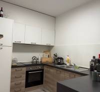 Küche in einer 2-Zimmer-Wohnung mit Holzboden und weißen Schränken.