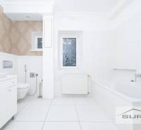 Badezimmer mit Dusche und Badewanne in einer 4-Zimmer-Wohnung, weiße Fliesen, gemusterte Tapete.