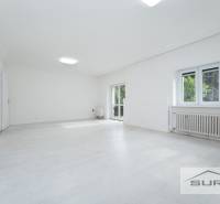 Geräumiges Wohnzimmer in einer 4-Zimmer-Wohnung mit weißem Boden und großen Fenstern.