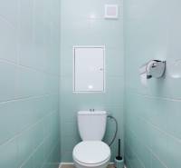 Toilette in einer 3-Zimmer-Wohnung mit hellblauen Fliesen und einem hellen Boden.