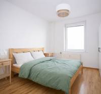 Schlafzimmer in einer 3-Zimmer-Wohnung mit Bett, Nachttischen und Boden mit Holzdekor.