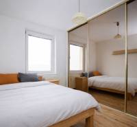 Schlafzimmer in einer 3-Zimmer-Wohnung mit Holzboden und großem Spiegelschrank.