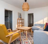 Wohnzimmer in einer 3-Zimmer-Wohnung mit Holzelementen, grauem Sofa und gelbem Sessel.