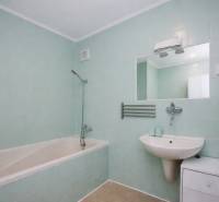 Badezimmer in einer 3-Zimmer-Wohnung mit Badewanne, Waschbecken, Spiegel und hellblauen Fliesen.