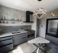 Küche in einer 2-Zimmer-Wohnung mit Betonoptik und geometrischer Leuchte.
