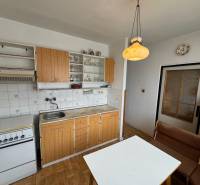 Küche in einer 2-Zimmer-Wohnung mit Küchenzeile, Tisch, Bank und Boden mit Holzdekor.