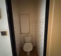 Toilette mit Fliesen und Holzboden in einer 2-Zimmer-Wohnung.