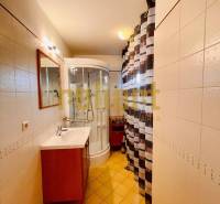 Ein Badezimmer in einem Einfamilienhaus mit Waschbecken, Duschkabine und Fliesen.