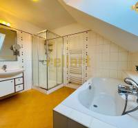 Ein Badezimmer in einem Einfamilienhaus mit Badewanne, Dusche und schräger Decke.