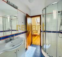 Badezimmer mit Dusche und Waschbecken, Boden mit Holzdekor in einem Einfamilienhaus.