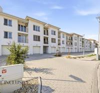 Ein Komplex aus weißen Gebäuden und Parkplätzen in Dunajská Streda, ideal für eine 4-Zimmer-Wohnung.