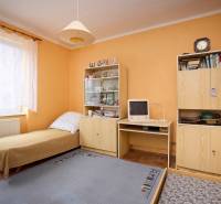 Ein Zimmer in einer 3-Zimmer-Wohnung mit einem Bett, Schränken, einem alten Computer und einer eingeschalteten Lampe.