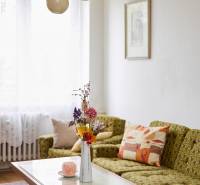 Helles Wohnzimmer in einer 3-Zimmer-Wohnung mit Sofa, Tisch und dekorativen Blumen in einer Vase.