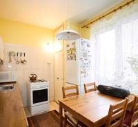 Küche in einer 3-Zimmer-Wohnung mit einem Holztisch, Herd und weißer Küchenzeile.
