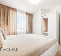 Helles Schlafzimmer in einer 4-Zimmer-Wohnung mit weißem Schrank und Vorhängen.
