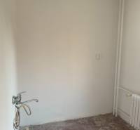 Ein leerer Raum in einer 2-Zimmer-Wohnung ohne Bodenbelag und mit Waschbecken.