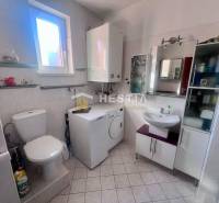 Das Badezimmer in der Einzimmerwohnung bietet eine Toilette, eine Waschmaschine und Regale am Fenster.