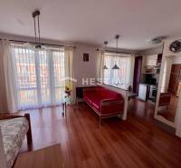 Innenraum einer 1-Zimmer-Wohnung mit Holzboden, Küche, hellen Vorhängen und bequemen Sitzgelegenheiten.