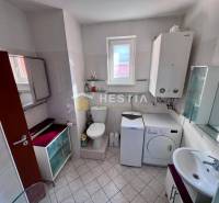 Das Badezimmer enthält eine Waschmaschine, Schränke, eine Toilette und ein Waschbecken, geeignet für eine Einzimmerwohnung.