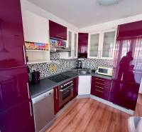 Küche in einer Einzimmerwohnung mit glänzenden Schränken und Mosaik an der Wand.