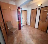 Flur in einer 2-Zimmer-Wohnung mit Fliesen, einem Kleiderschrank und einem Stuhl.