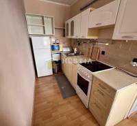 Küche in einer 2-Zimmer-Wohnung mit Holzboden und hellen Schränken.