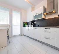 Küche in einer Einzimmerwohnung mit weißen Schränken und dunkler Arbeitsplatte.