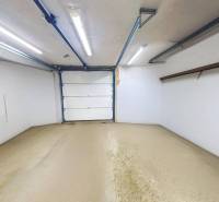 Die Garage im Einfamilienhaus hat weiße Wände, Beleuchtung und einen erhöhten Stauraum.