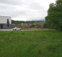 Grundstücke - Wohnen in Žilina auf der Chotárna zeigen eine grüne Wiese mit einem modernen Gebäude und einem Auto.