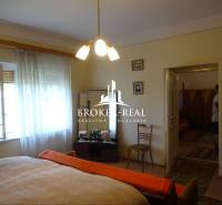 Schlafzimmer in einem Einfamilienhaus mit Holzboden, Bett, Sessel, Stühle.