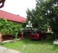 Der Garten des Einfamilienhauses in Goncruszka mit rotem Dach und einem Auto auf dem Rasen.