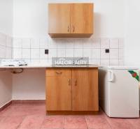 Küchenbereich mit Fliesen, Schränken und einem kleinen Kühlschrank in Hotels und Pensionen.