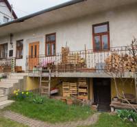 Ein Einfamilienhaus in Kostoľany nad Hornádom, mit Holz auf der Terrasse und einem Garten.