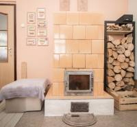 Ein gemauerter Kamin mit Holz, Türen und ein Hocker im Inneren eines Einfamilienhauses.