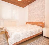 Schlafzimmer in einem Einfamilienhaus mit Holzdecke, dekorativer Tapete und gestreiften Teppichen.