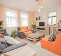 Wohnzimmer in einem Einfamilienhaus mit orangefarbenen Sofas, Pflanzen und einem Holzboden.
