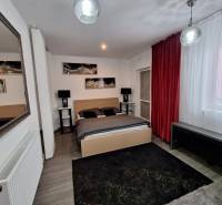 Schlafzimmer im Einfamilienhaus mit Spiegel, roten Vorhängen und Wanddekorationen.