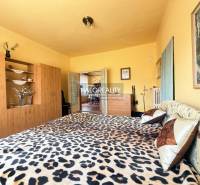 Ein Schlafzimmer in einem Einfamilienhaus mit einem Bett im Leopardenmuster und einem Schrank in Holzoptik.