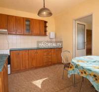 Küche in einem Einfamilienhaus mit Einbauschränken und einem Tisch mit geblümter Tischdecke.